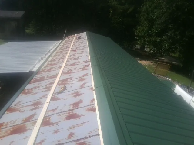 Old rusted panels beside newly installed green metal roofing — Wind Damage Roof Repair by Roofing Brothers in Marshall