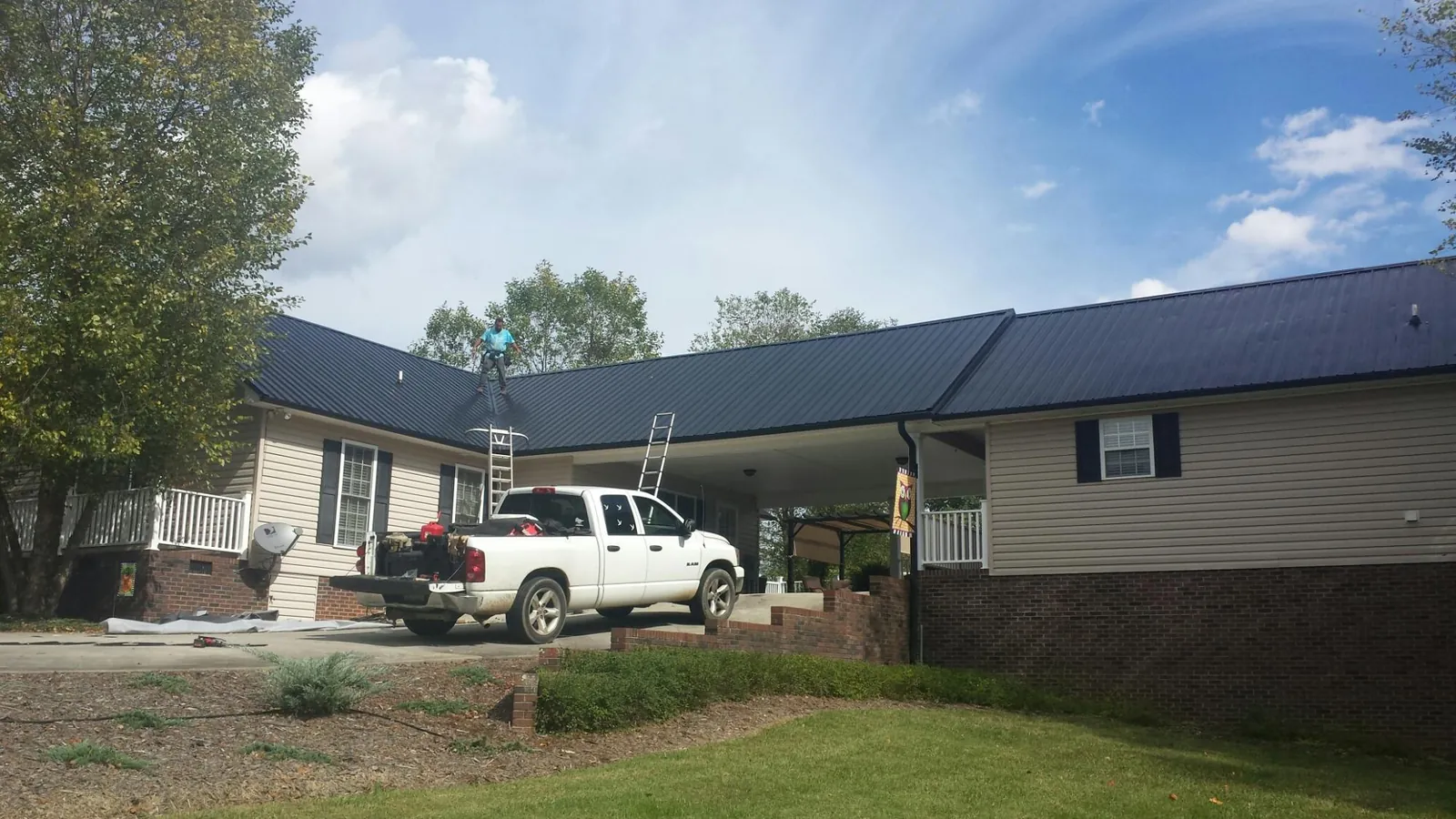 Black metal roof over a home and attached breezeway with ladders set in Marshall
