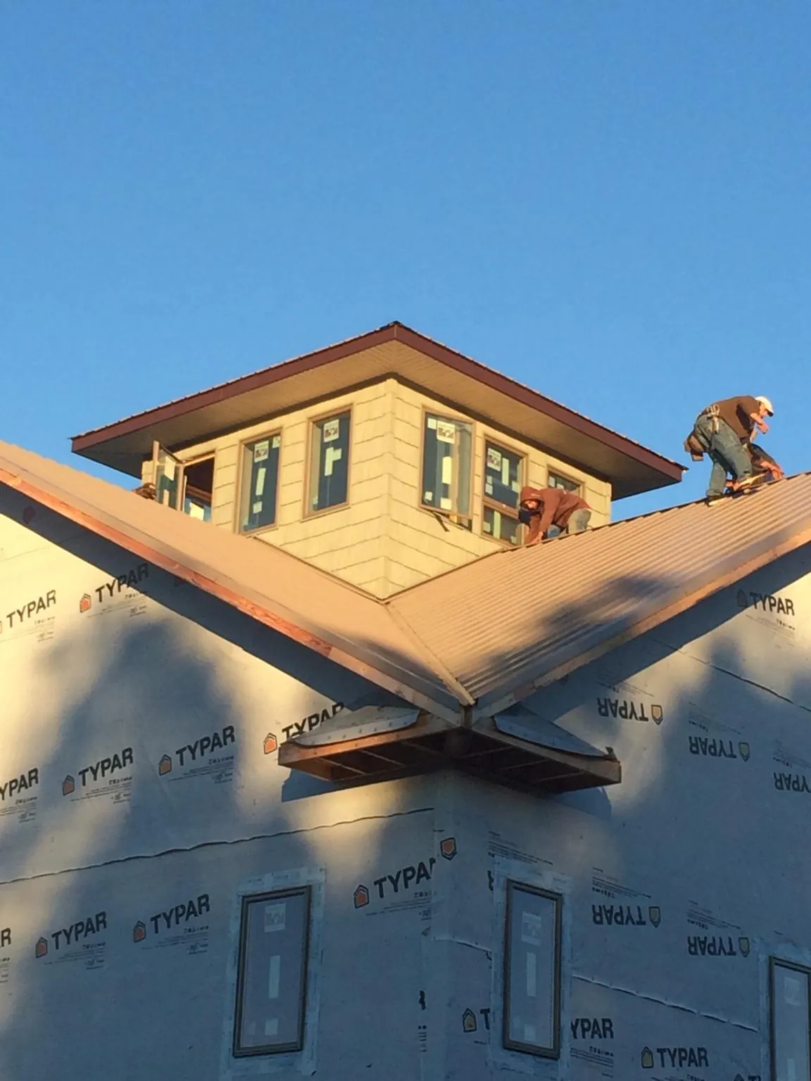 Roofers working around a rooftop cupola on a new metal roof at sunset — Roof Waterproofing in Marshall by Roofing Brothers